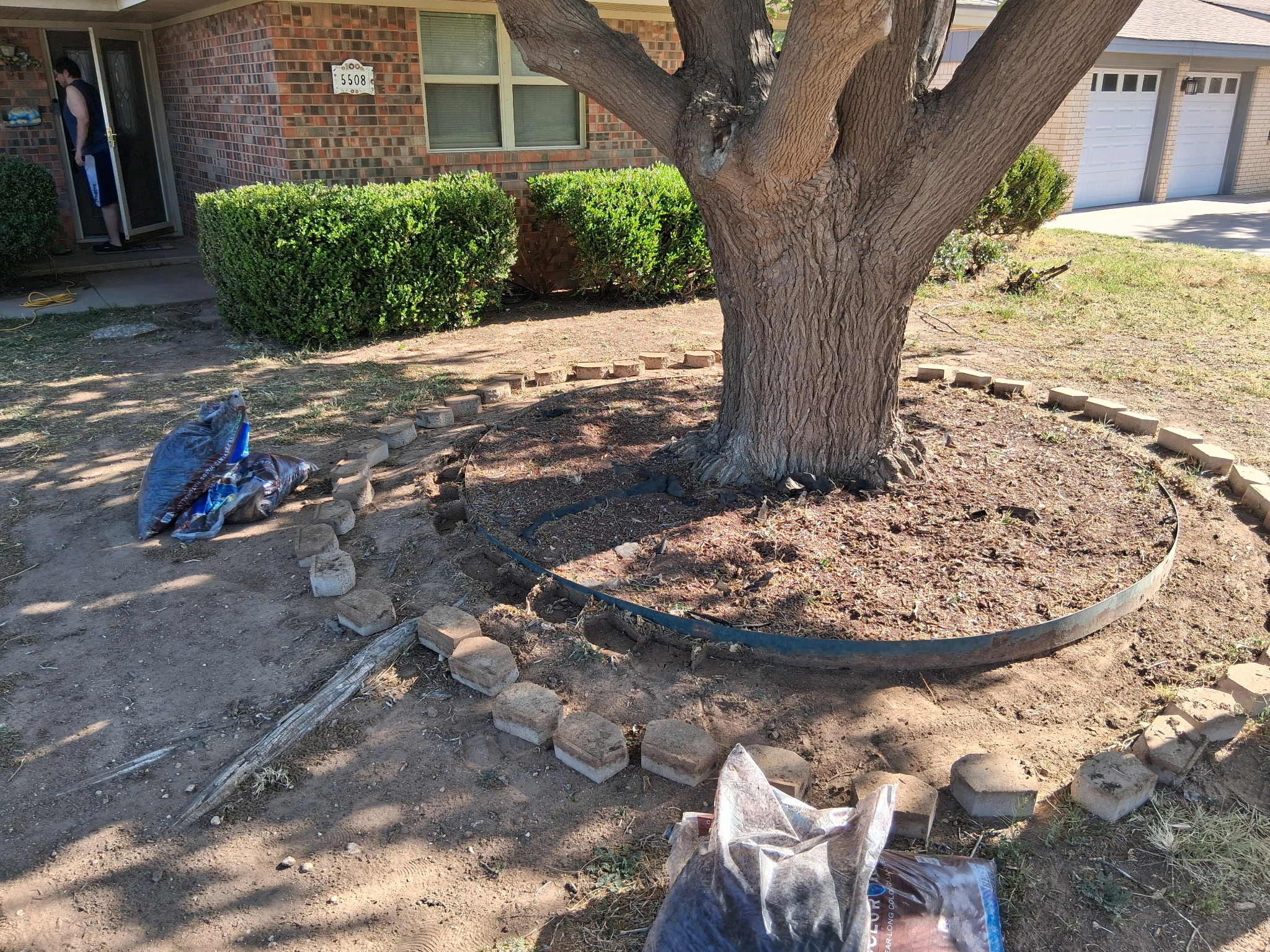 Stone border and metal edging being installed around a tree at a Lubbock, TX home