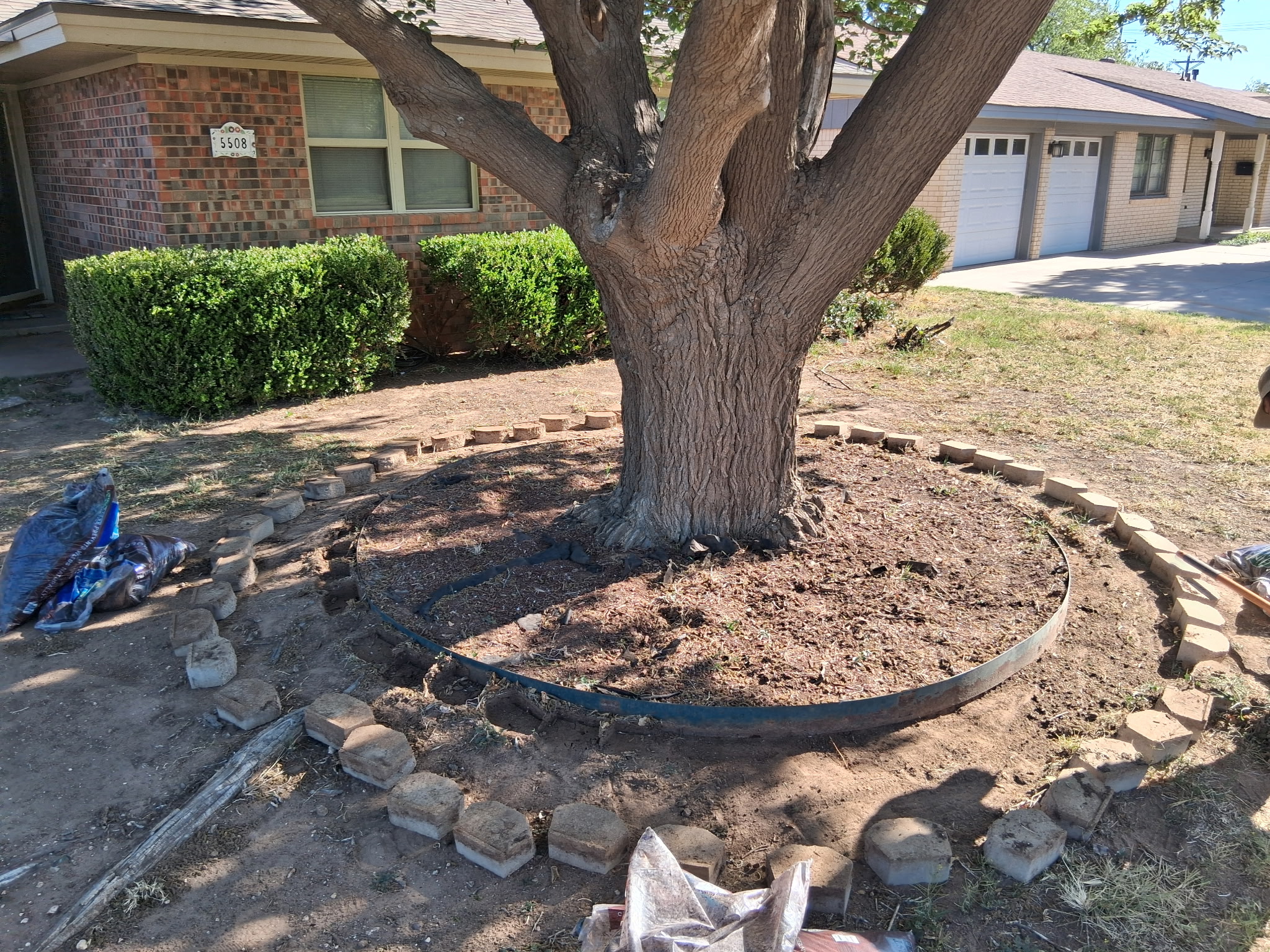 Stone pavers and metal edging being placed around a tree in Lubbock, TX