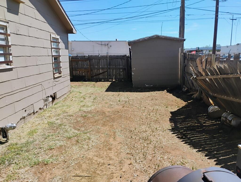 Bare back lot with shed and fence before landscaping work in Lubbock, TX